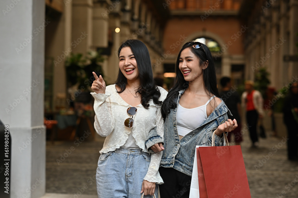 Obraz premium Two Asian teenage girls smile happily in an open-air shopping mall