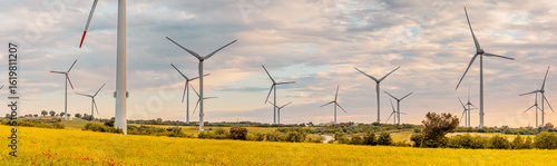 Bild auf Leinwand Wind turbines stand tall in a field of yellow flowers, generating clean energy a