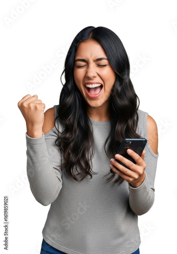 Young latin woman, early twenties, long dark wavy hair, grey long-sleeved top, shouting in triumph, clenched fist, holding black smartphone, isolated on clean white background with copy space concept