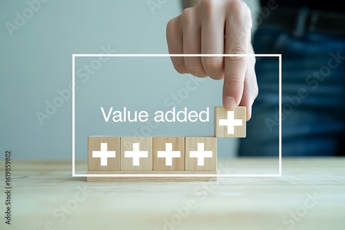 Hand adding wooden block with plus sign to row of blocks showing value added image
