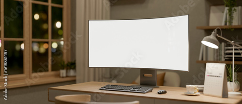 Fototapeta Naklejka Na Ścianę i Meble -  Blank curve screen computer aside coffee, calendar and lamp on wooden table in a room with bookshelf