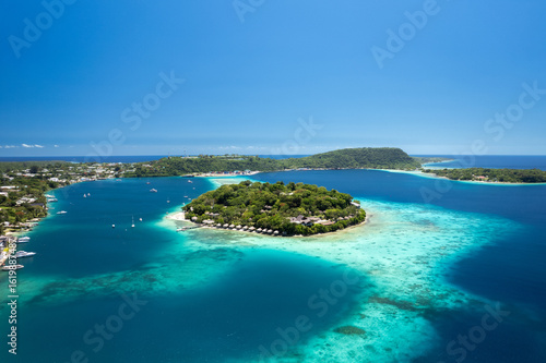 Drone photo of Iririki Island resort in Port Vila Harbour, Vanuatu. Idyllic holiday destination with clear water, boats, and waterfront bungalows.