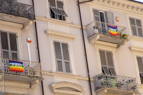 Rainbow Pace Flag. International Peace Day. Rainbow flag on the balcony of an old house. Windows with shutters. Facade of the building. Italy La Spezia.
