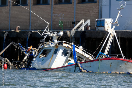 Sunken fishing boat partially submerged in harbor, maritime accident scene