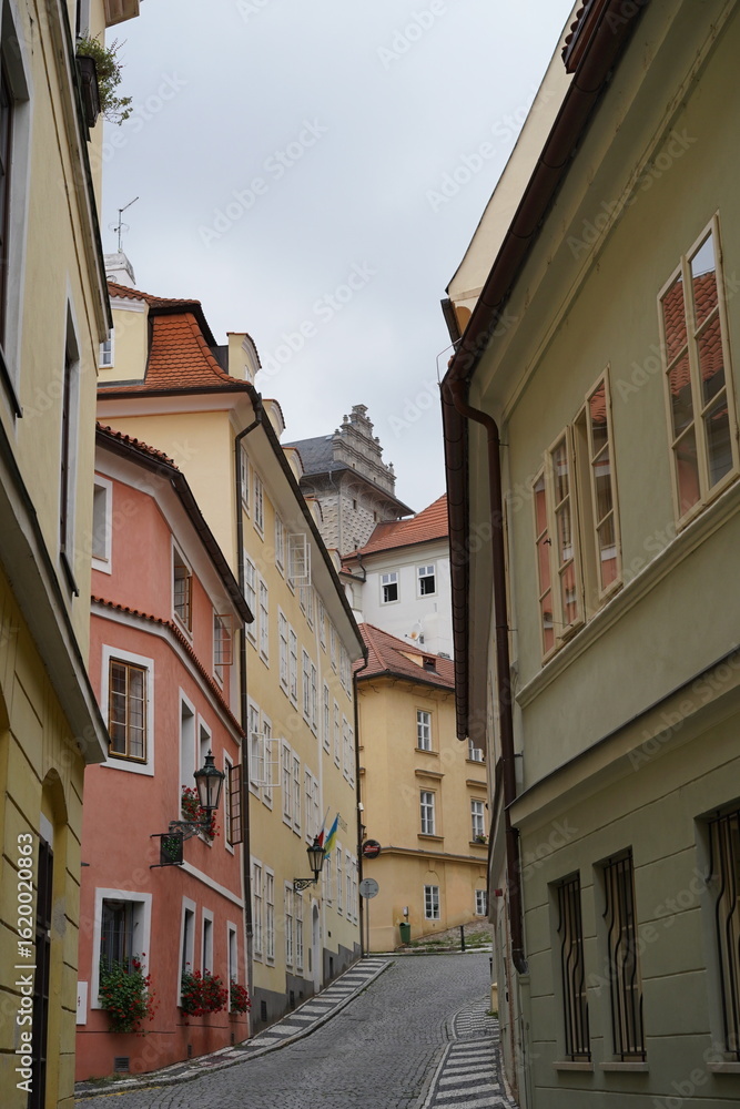 Naklejka premium Charming cobblestone street in a historic neighborhood featuring colorful buildings and a castle in the background
