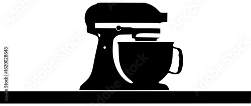 Mixer in the kitchen on the table with big bowl working with dough and spoon in storage cabinet with long cord near oven in the corner