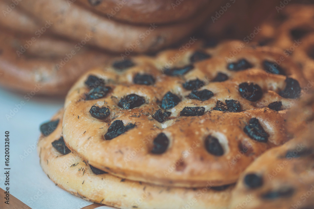 Freshly baked bread with olives displayed on a wooden table in a cozy bakery setting during the morning hours in a pleasant neighborhood Freshly baked bread with olives displayed on a wooden table in a cozy bakery setting during the morning hours in a pleasant neighborhood