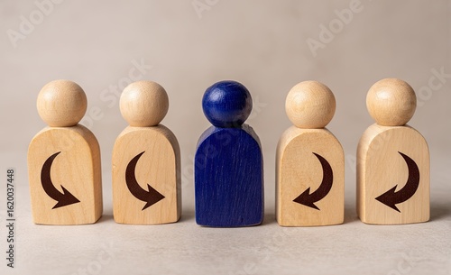 A single, distinct, blue wooden figure stands out among four identical light-brown figures.  Each figure has a stylized arrow on either side