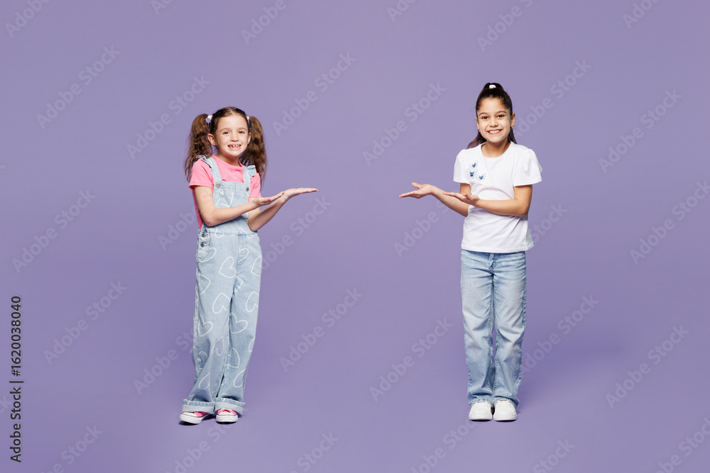 Naklejka premium Full body smiling little two friends kids children girls 9-10 years old wear casual clothes together point hands arms on each other look camera isolated on plain purple background. Lifestyle concept.