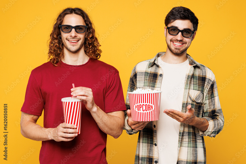 Obraz premium Young happy cheerful two friends buddies men they wear casual clothes 3d glasses watch movie film hold bucket of popcorn cup of soda pop in cinema together isolated on plain yellow orange background.