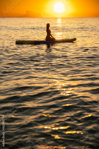 Wallpaper Mural Young woman sitting on paddleboard in ocean at sunrise Torontodigital.ca
