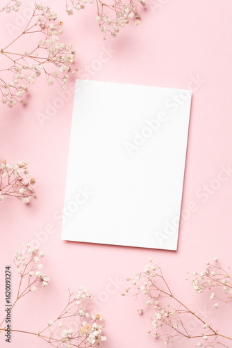 Fotografi Blank white wedding invitation card mockup surrounded by delicate flowers on sof