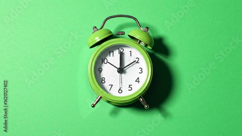 Green alarm clock on green background