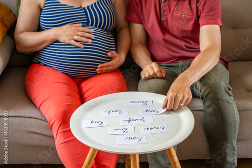 Relaxed Pregnant Couple at Home Choosing Name for Their Baby, Selective Focus