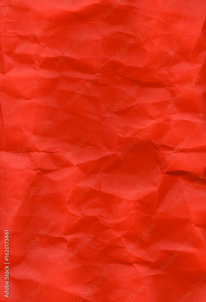 Fototapeta premium Crumpled red paper featuring a vivid hue with visible folds and wrinkles. The texture is irregular, providing a realistic, tactile appearance. Suitable for use in design templates, such as flyers.