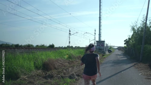 An athlete does her daily training in a rural area next to the train tracks.