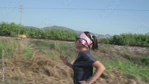 A woman runs alongside the railroad tracks as a passenger train makes its daily journey.