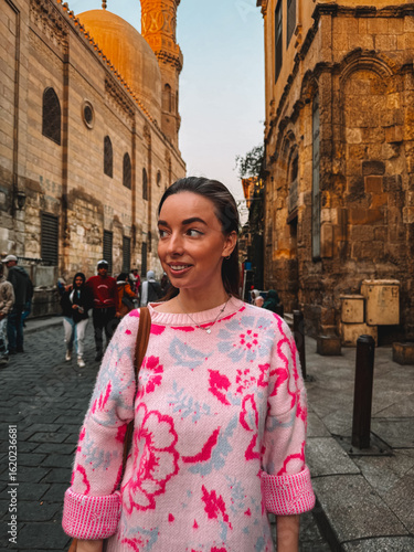 Woman in bright pink sweater on historic Cairo street
