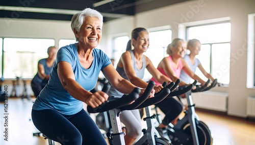 Happy senior women enjoy a fitness class, riding stationary bikes