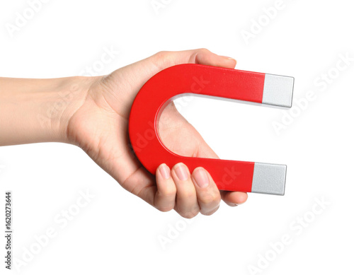 A hand holding a red horseshoe magnet with silver ends, representing magnetism and attraction.