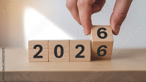 Countdown to 2026: Hand turns wooden block to reveal the year 2026