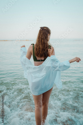 beautiful young girl with a beautiful athletic figure of European appearance in a swimsuit and underwear on the ocean shore in the open air. Sea waves and rocks with blue water. Travel and recreation