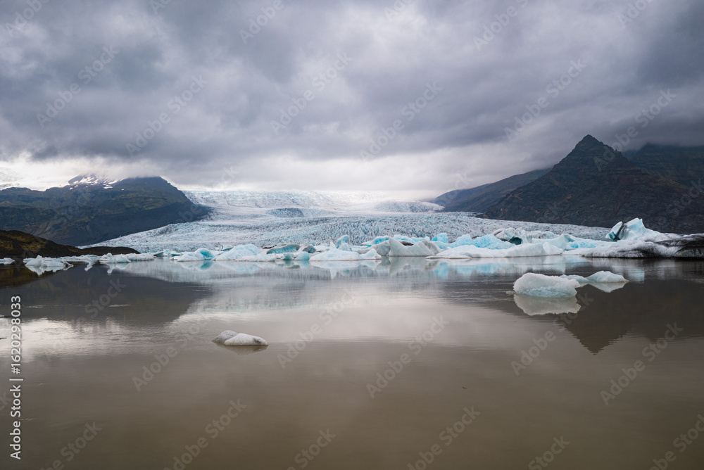 Fototapeta premium Dramatic Glacier Landscape with Icebergs Under Stormy Sky