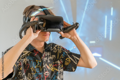 Serious Gamer Immersed in VR Under Futuristic Neon Light. Guy in 3D virtual reality glasses. A young man interacting with advanced virtual reality interface.