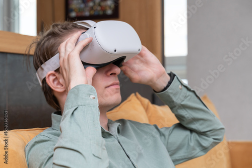 Young man in 3D virtual reality glasses. VR glasses and helmet. Futuristic and modern. Caucasian man is playing a virtual game on home background.