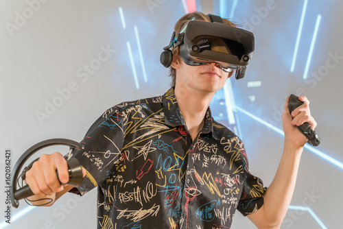 Male Gamer Immersed in VR in Cyberpunk Setting. Guy in 3D virtual reality glasses. Concentrated male standing in neon space, experiencing virtual dynamics via VR equipment.