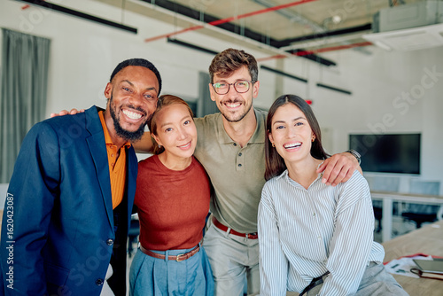 Multi-ethnic businesspeople embracing each other showing teamwork and unity in startup company workplace