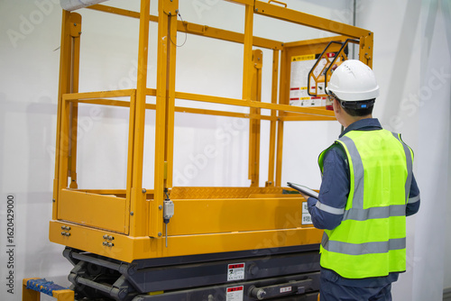 Εκτύπωση καμβά Worker inspecting yellow personal lift equipment in industrial setting with safe