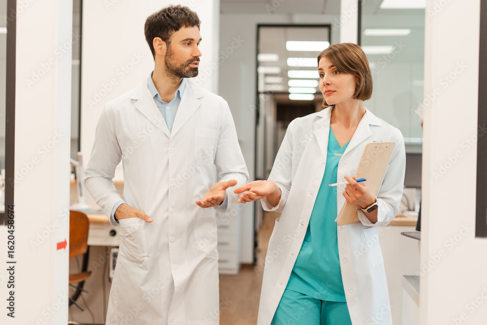 Fototapeta premium Doctors wearing lab coats are walking and discussing in hospital corridor