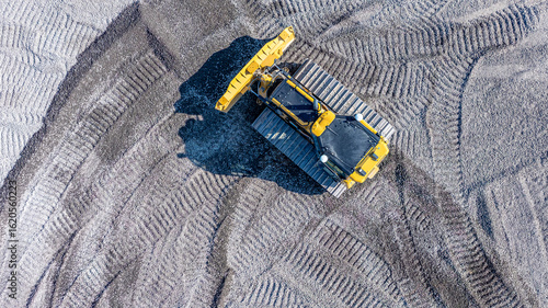 Aerial, overhead image of a bulldozer working on construction site. Smoothing gravel surface for new road. Earthmoving, excavations, digging on soils	