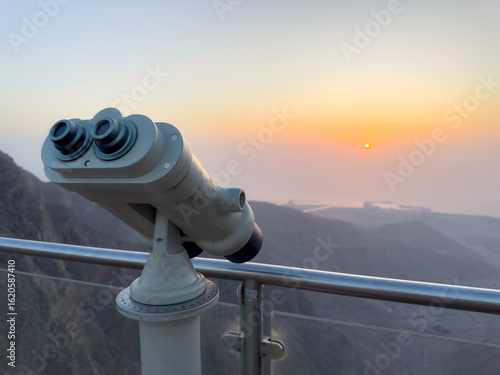 Viewing telescope at sunset on mountaintop overlooking ocean and horizon in soft pastel colors of dusk