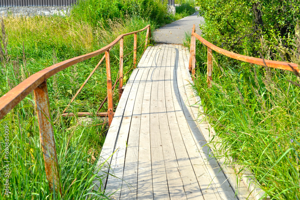 Obraz premium rural wooden bridge over a river with metal railings