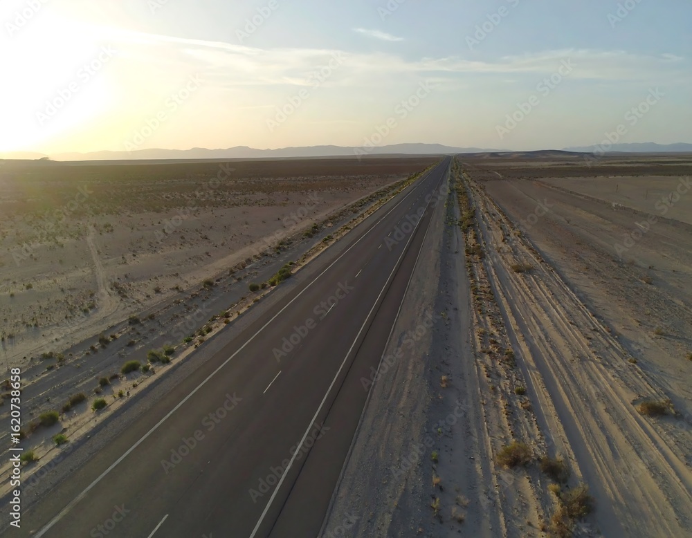 Fototapeta premium Highway stretching through desert landscape at sunset
