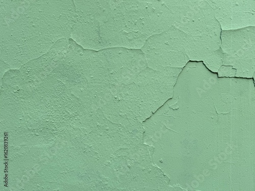 Old green painted wall close up image with cracks and weathered texture background. Rural, vintage, urban, and rustic design backgrounds theme