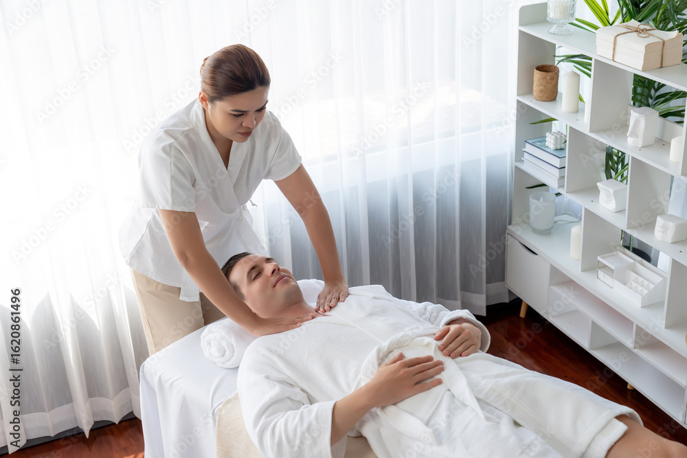 Obraz premium Caucasian man customer enjoying relaxing anti-stress spa massage and pampering with beauty skin recreation leisure in day light ambient salon spa at luxury resort or hotel. Quiescent