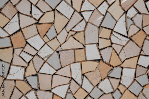 Abstract mosaic background of broken ceramic tile pieces. A textured wall pattern in neutral beige, cream, and white tones.