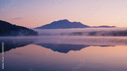 Wallpaper Mural Pastel reflection of mountain silhouette on mist-covered lake under pale pink sky Torontodigital.ca