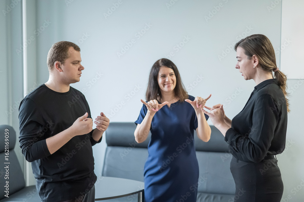 © Михаил Решетников - Caucasian woman teaching sign language to man and woman.