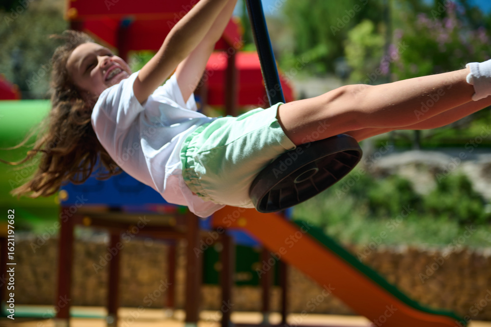 Fototapeta premium Happy Child Enjoying Playtime on a Swing in a Vibrant Summer Playground