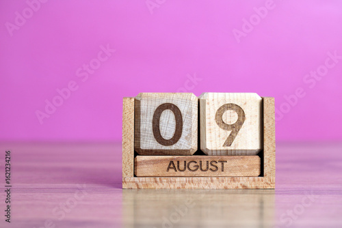 Wooden calendar showing the ninth of august, on a pink background