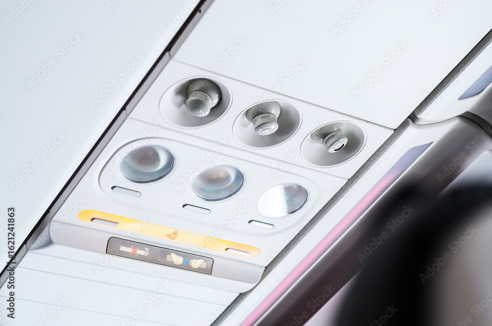 Fototapeta premium Brightly lit control panel for passenger seat in airplane cabin interior