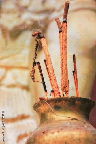 Brown incense sticks in a gold jar