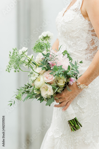 Bride in lace gown holding a pastel pink and white wedding bouquet