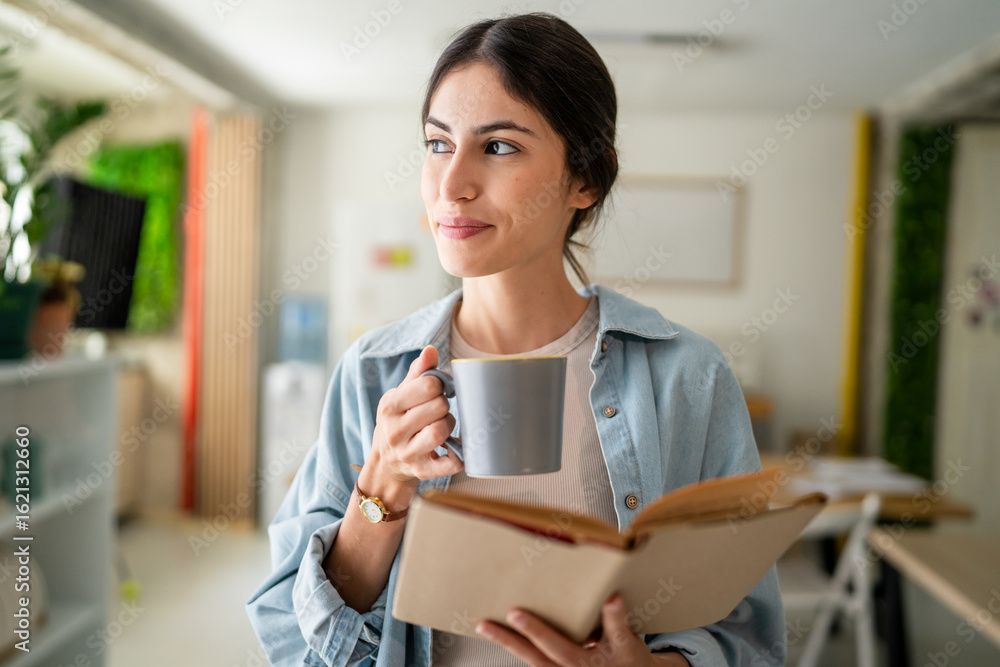 Fototapeta premium Adult happy woman drinking coffee and reading a book during a break