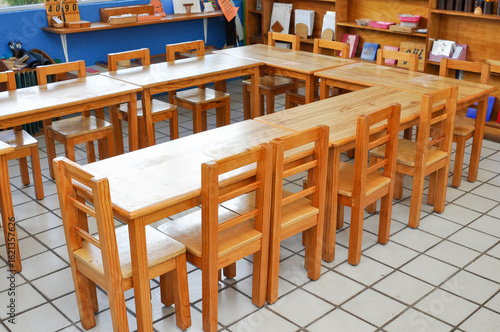 Empty Montessori classroom with wooden chairs and tables arranged in U-shape