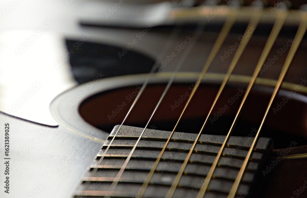 Fototapeta premium A black guitar up close with the strings in the background